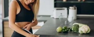 Femme en tenue de sport mesurant sa taille près d'aliments sains, illustrant l'utilisation de probiotiques pour maigrir. immunocure.com